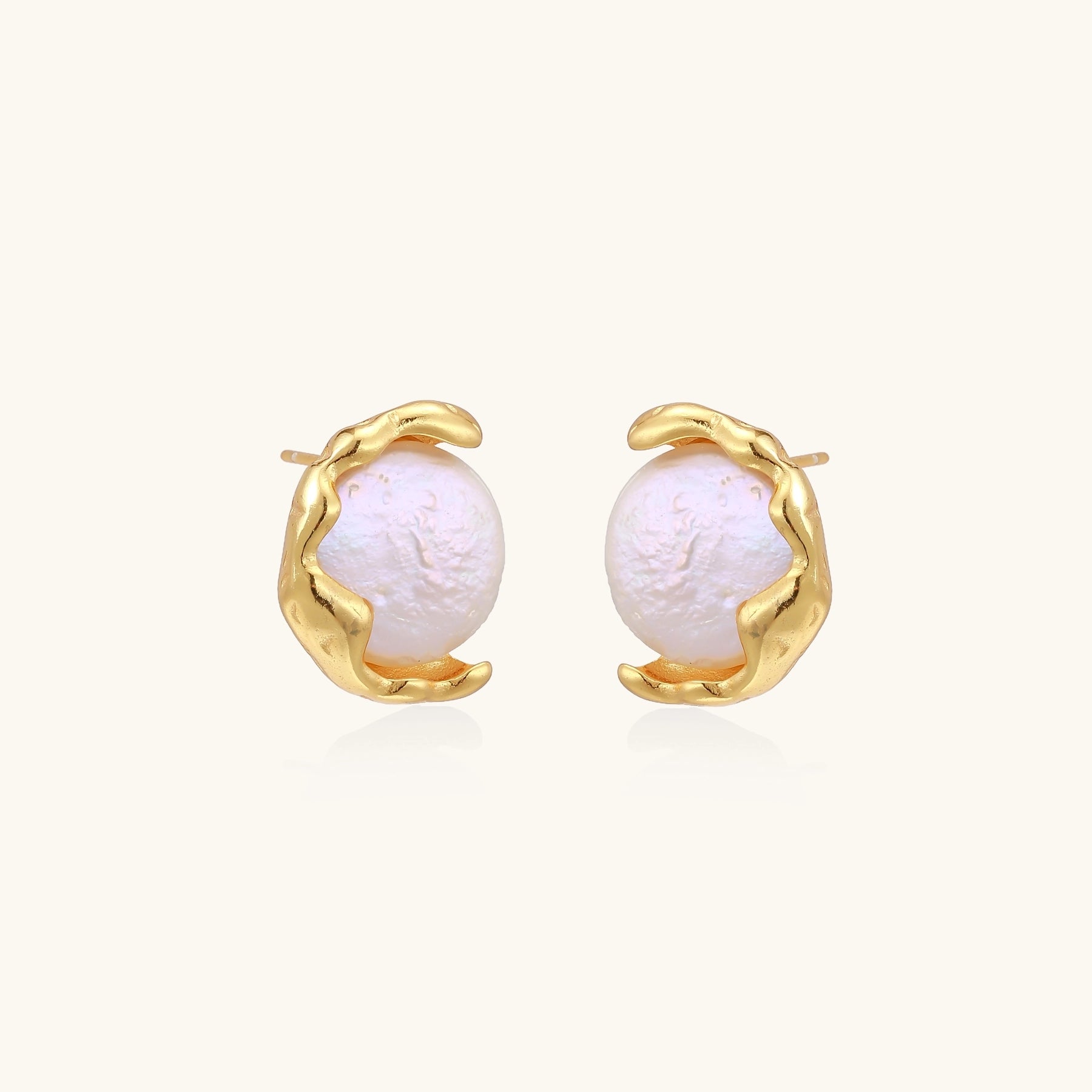 Gold-plated sterling silver stud earrings with organic claw settings cradling lustrous freshwater pearls on white background.