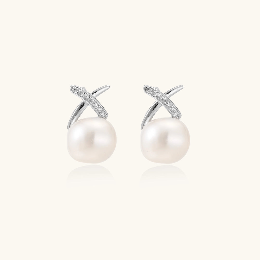 Sterling silver cross-shaped stud earrings with round freshwater pearls dangling below on white background.