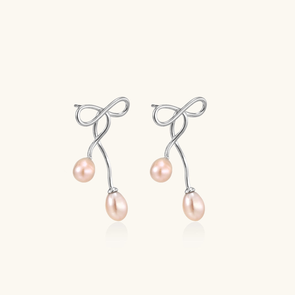 Delicate sterling silver wire earrings with organic bow shapes and two pink freshwater pearls on white background
