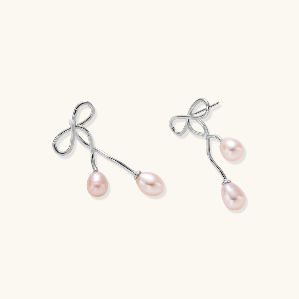 Delicate sterling silver wire earrings with organic bow shapes and two pink freshwater pearls on white background