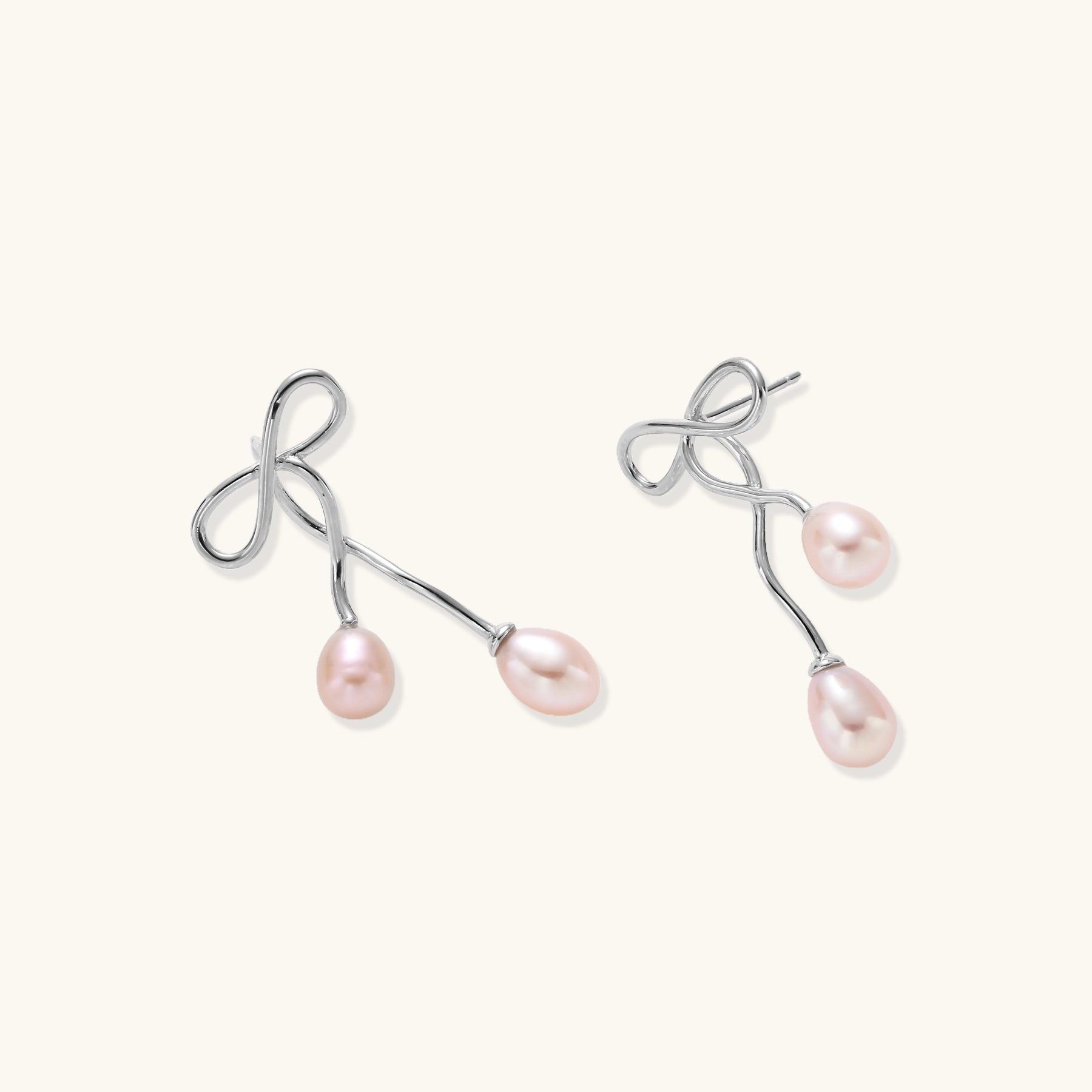 Delicate sterling silver wire earrings with organic bow shapes and two pink freshwater pearls on white background