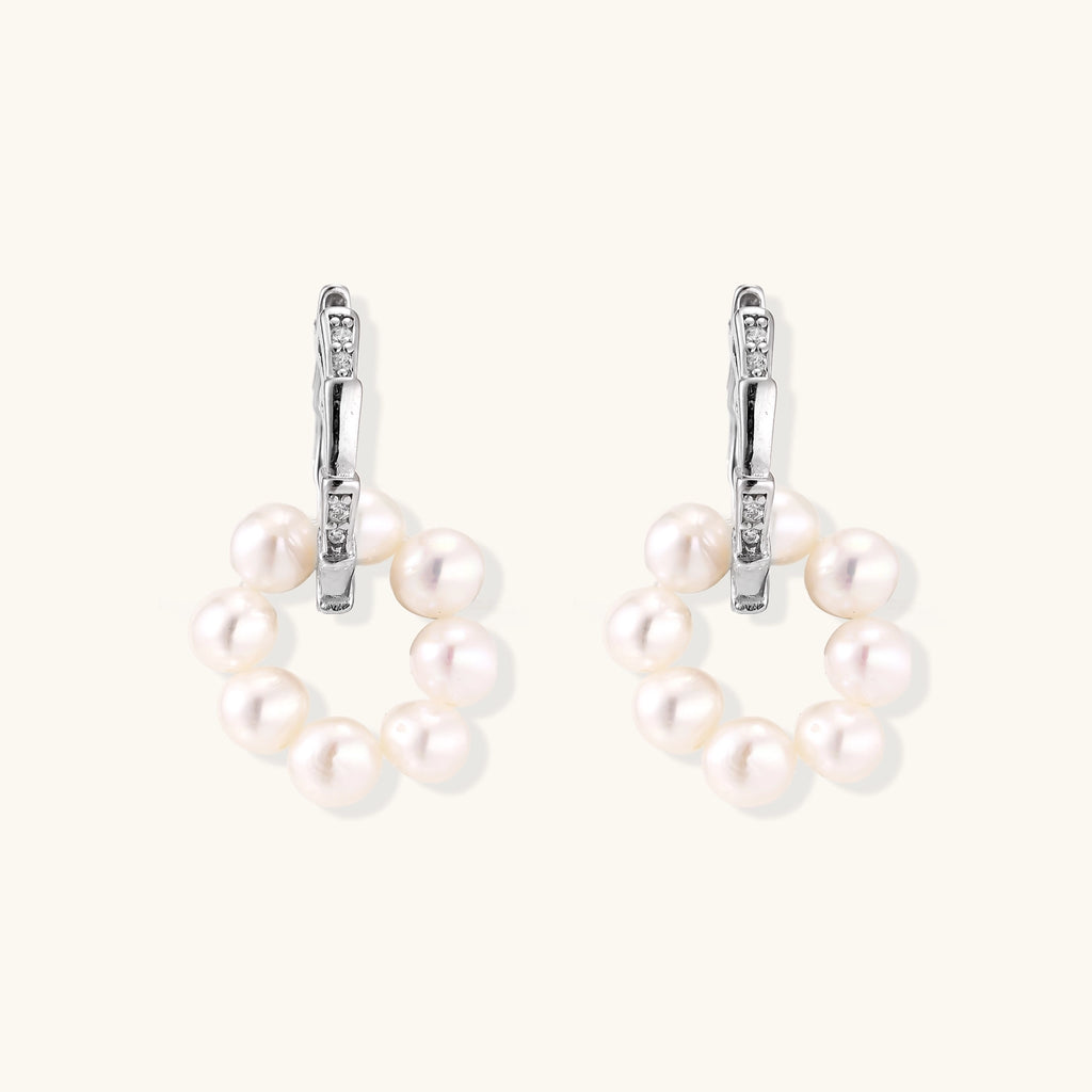 Sterling silver huggie hoop earrings with clustered white freshwater pearls and crystal accents on white background.