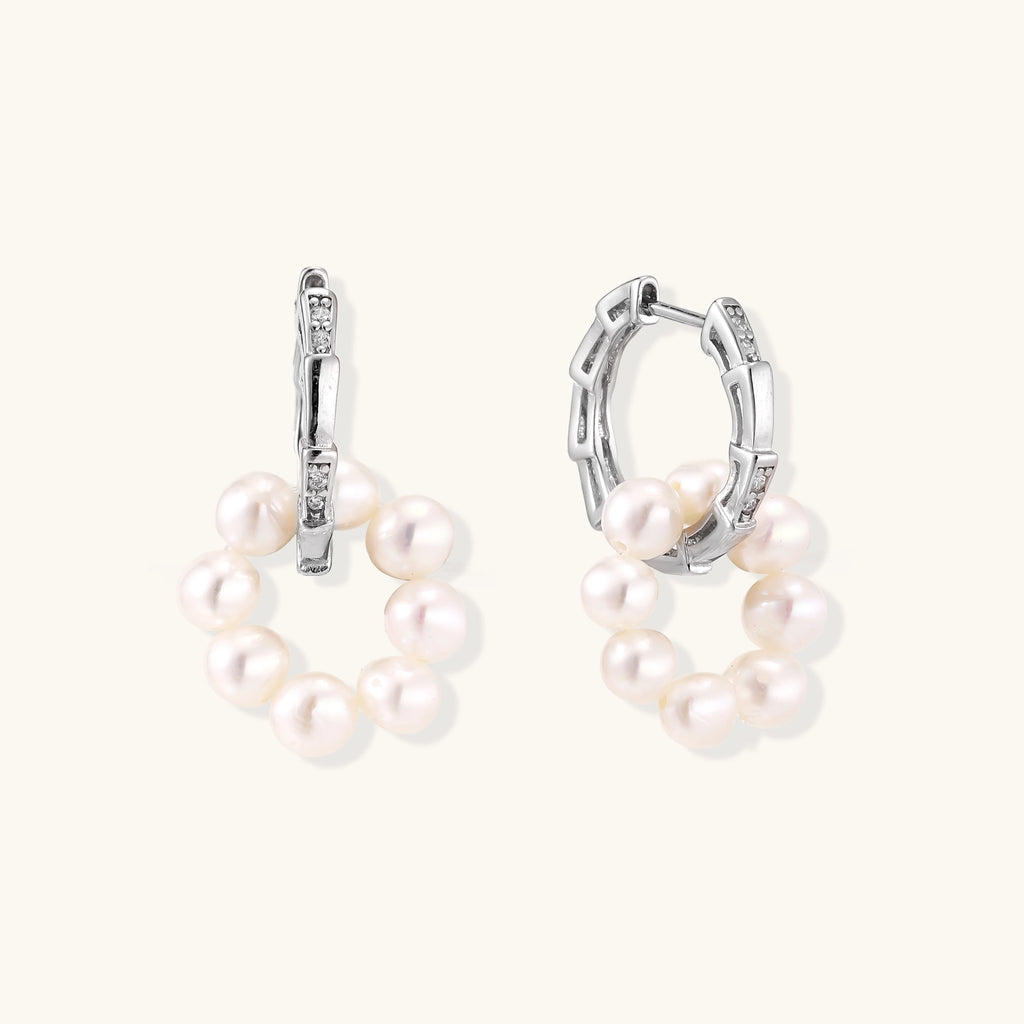 Sterling silver huggie hoop earrings with clustered white freshwater pearls and crystal accents on white background.