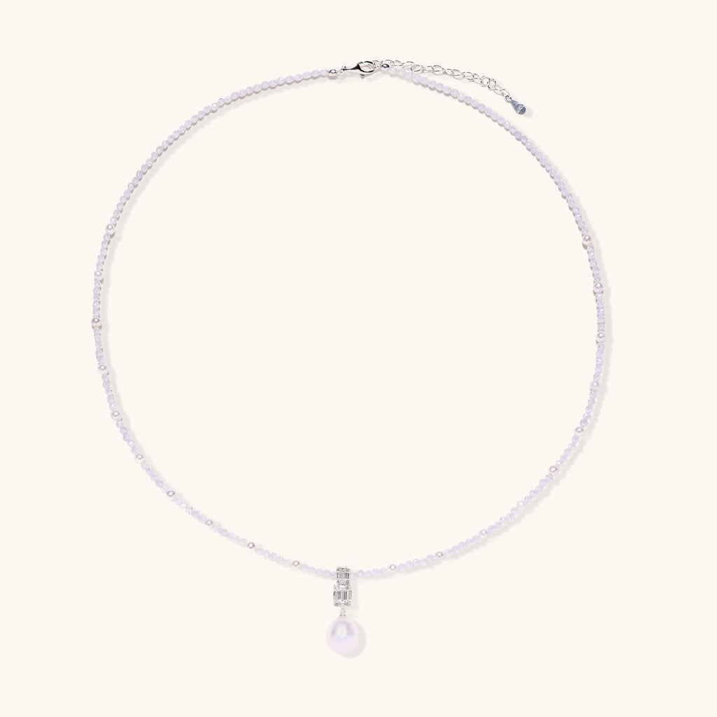 Delicate beaded necklace with lavender crystals, white pearls, and crystal pendant with pearl drop on white background.