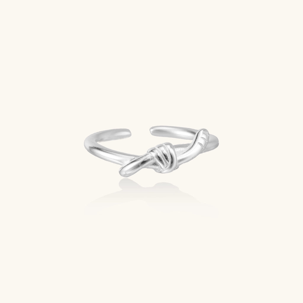 Delicate sterling silver ring with geometric knot design on white background, showcasing adjustable open band.