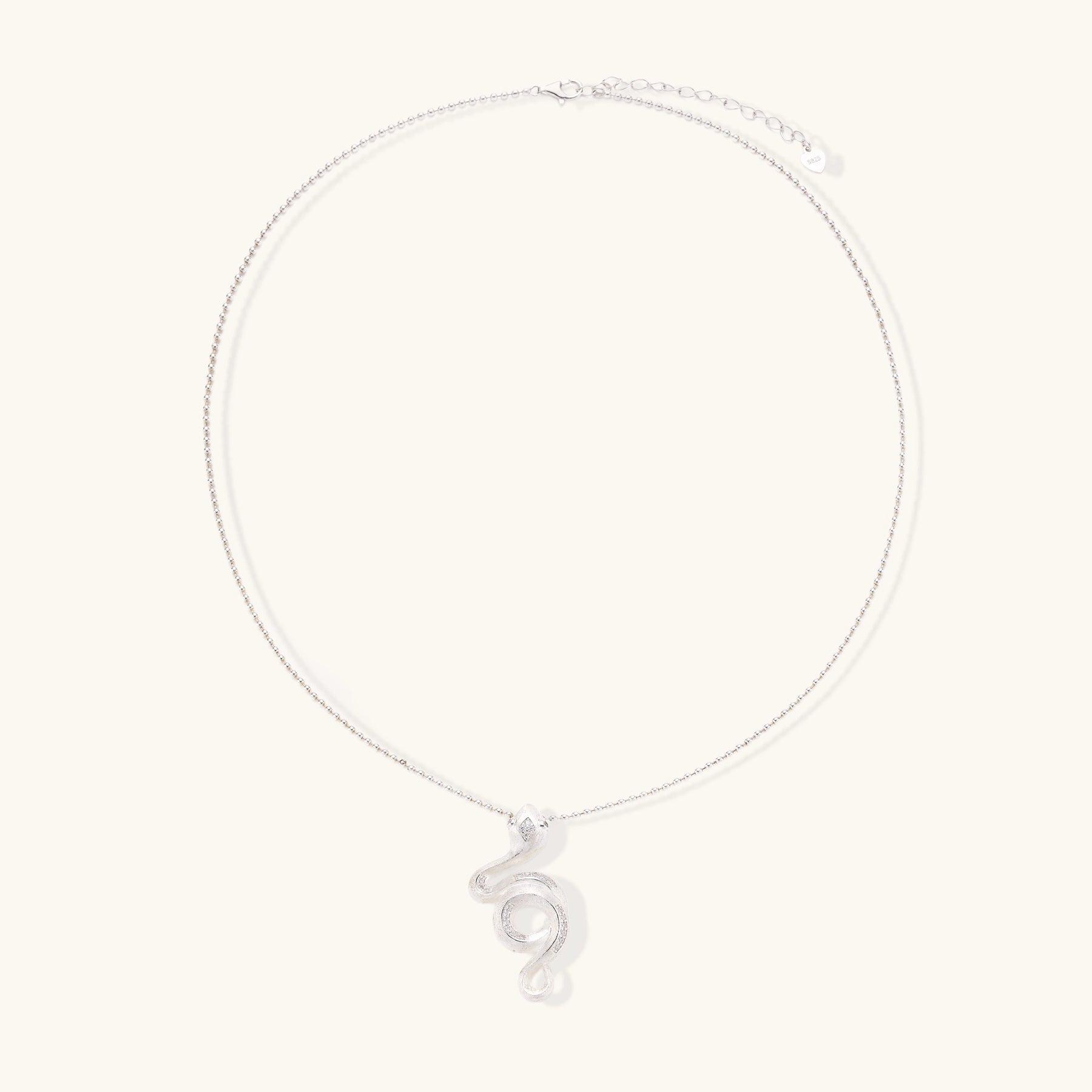 Sterling silver snake pendant necklace with zirconia crystals on adjustable chain against cream background