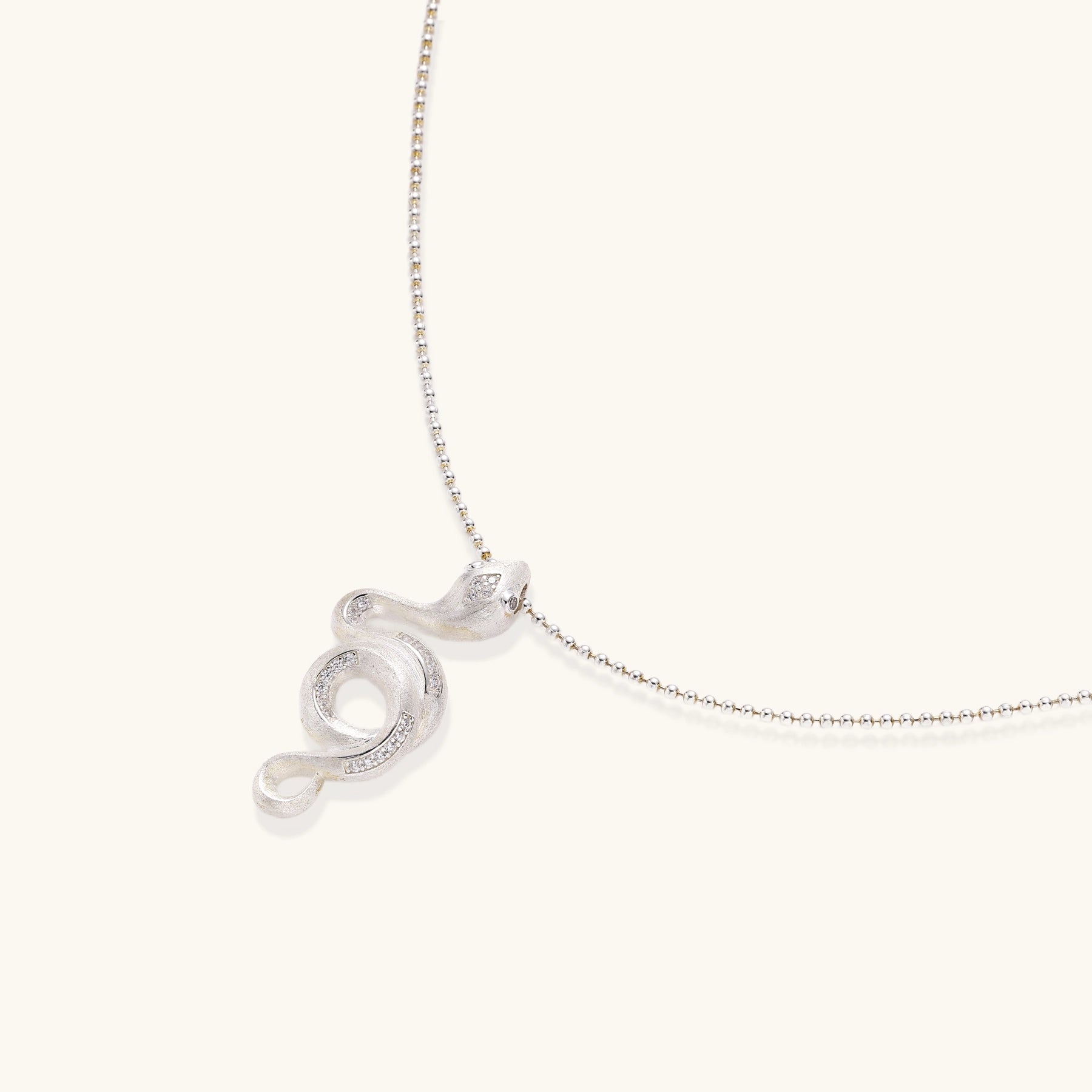 Sterling silver snake pendant necklace with zirconia crystals on adjustable chain against cream background