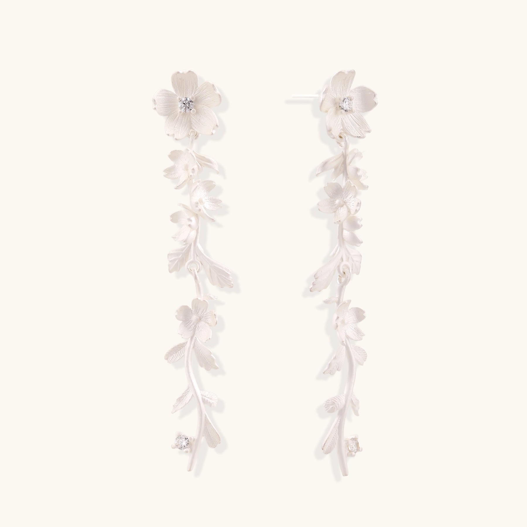 Pair of sterling silver dangle earrings with intricate leaf vine patterns and crystal accents on white background.