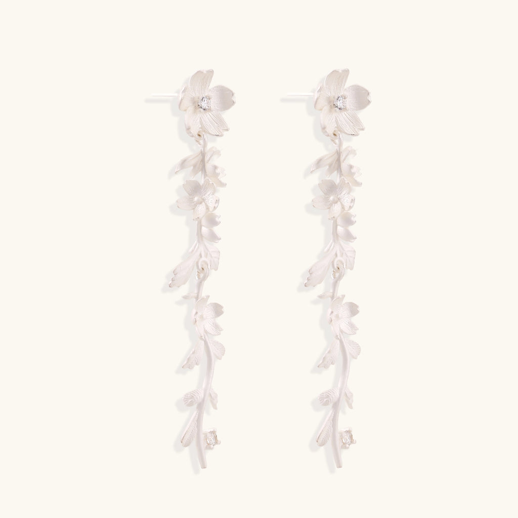 Pair of sterling silver dangle earrings with intricate leaf vine patterns and crystal accents on white background.