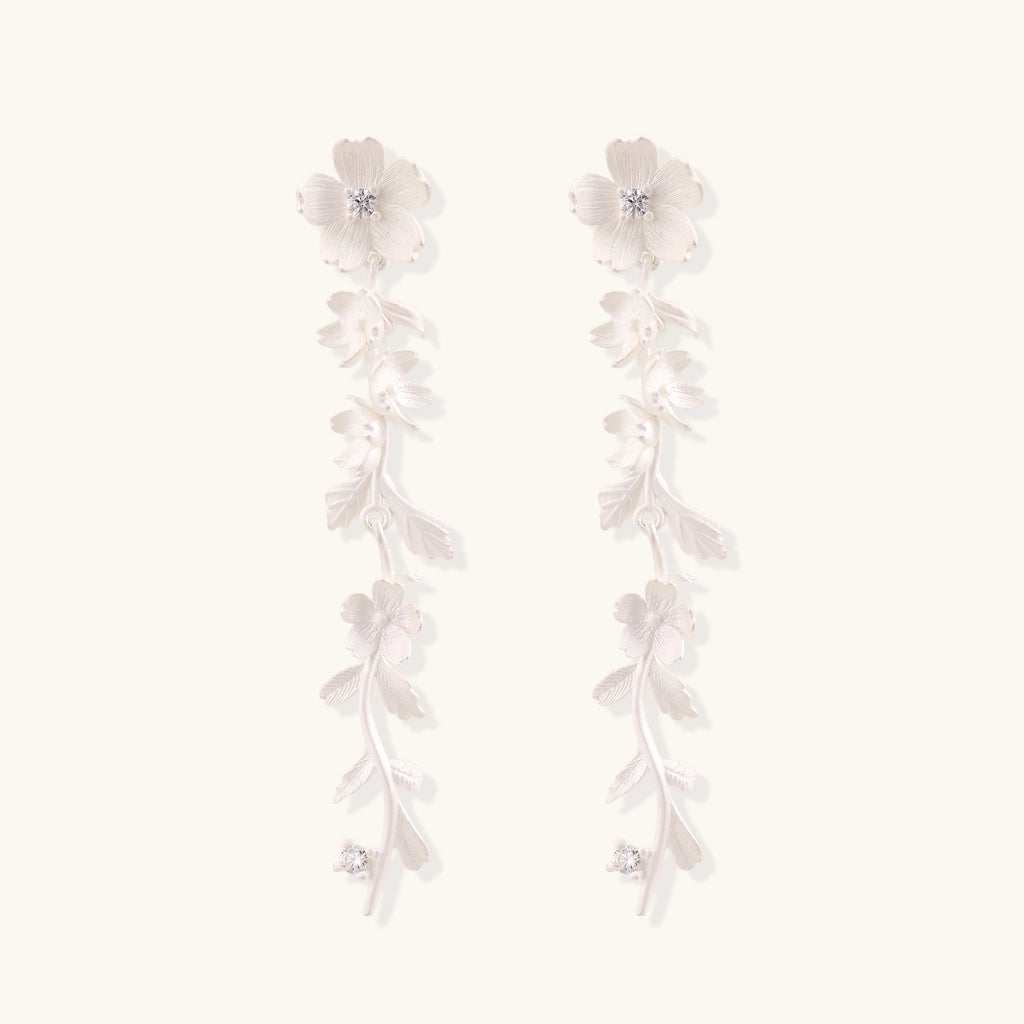 Pair of sterling silver dangle earrings with intricate leaf vine patterns and crystal accents on white background.