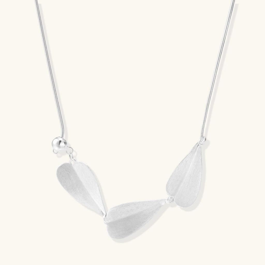 Delicate sterling silver necklace with brushed leaf pendants distributed along a fine chain on white background.