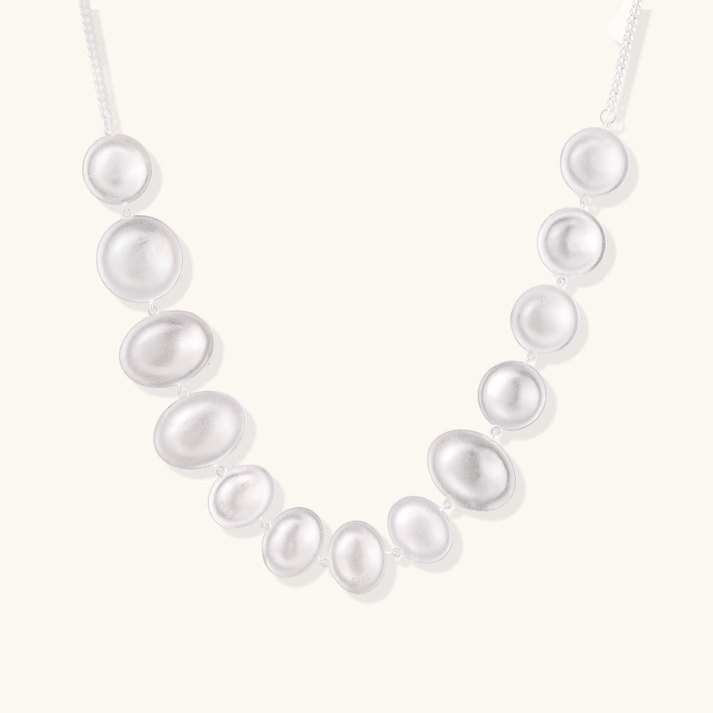 Sterling silver necklace with asymmetrically placed white pearls of varying sizes on neutral background