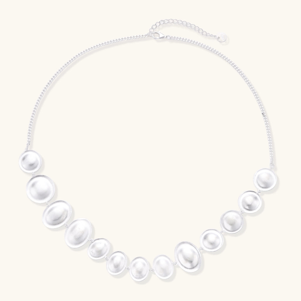 Sterling silver necklace with asymmetrically placed white pearls of varying sizes on neutral background
