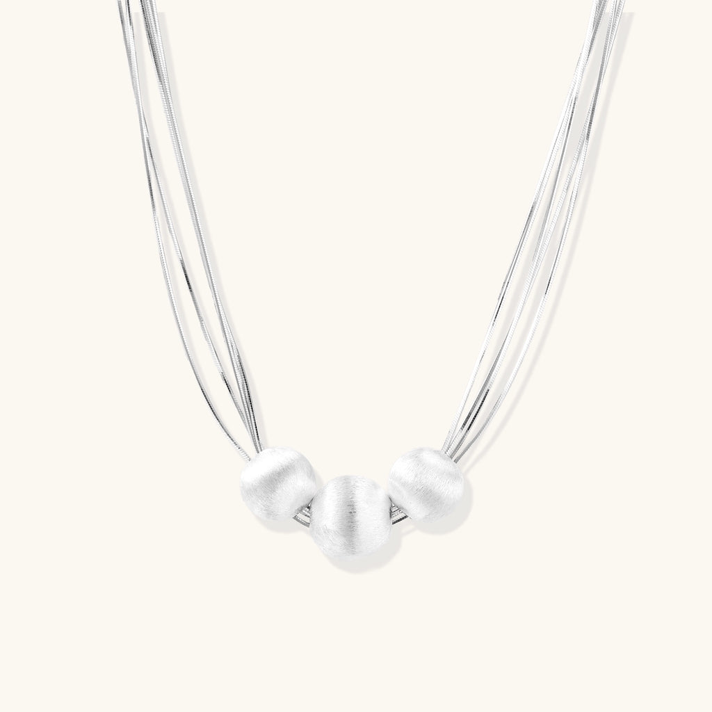 Multi-strand sterling silver necklace with three polished round beads clustered at center on white background.