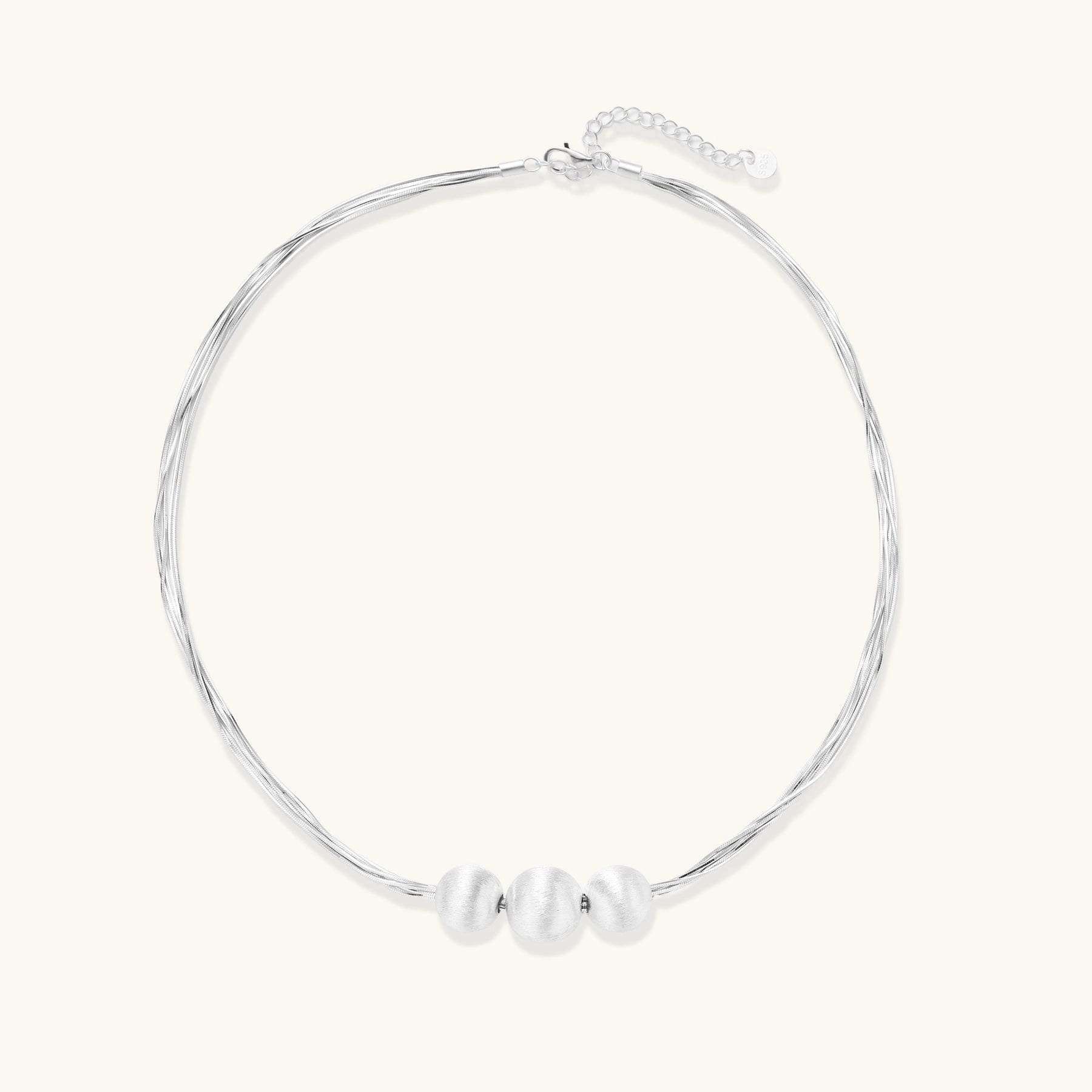 Multi-strand sterling silver necklace with three polished round beads clustered at center on white background.