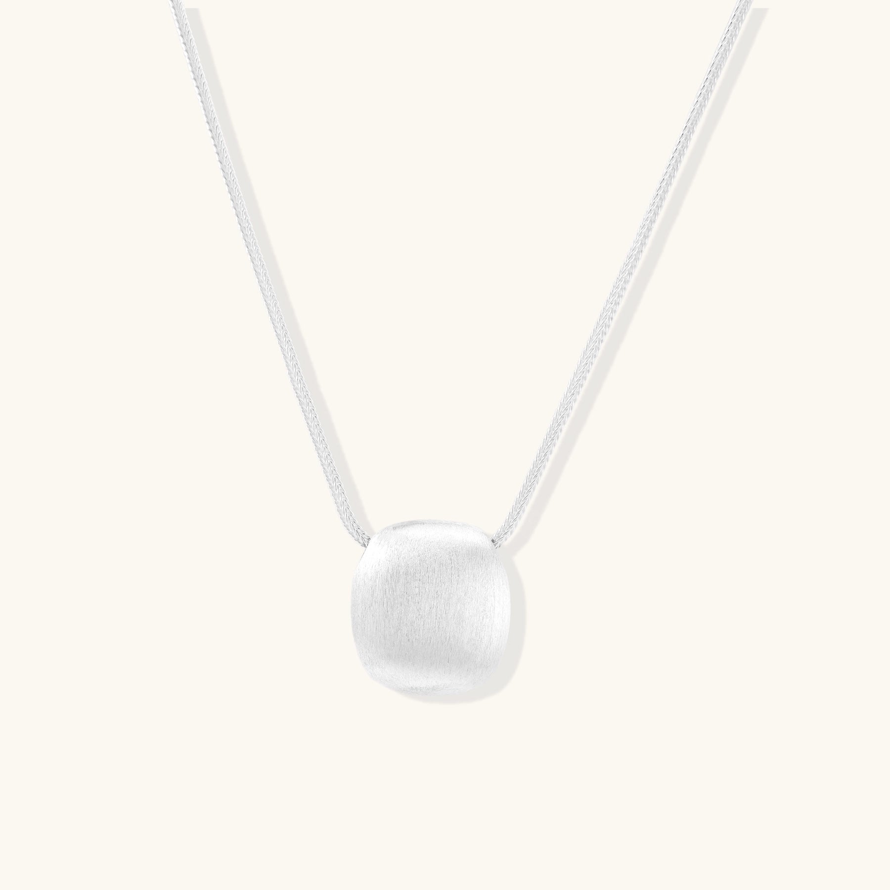 Minimalist sterling silver necklace with brushed square pendant on adjustable chain against white background.