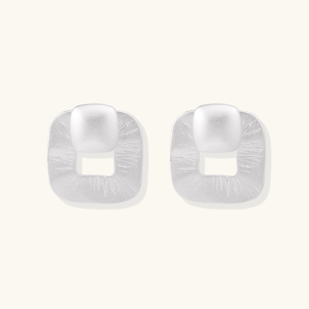 Geometric sterling silver square stud earrings with brushed texture and central square cutouts on white background.