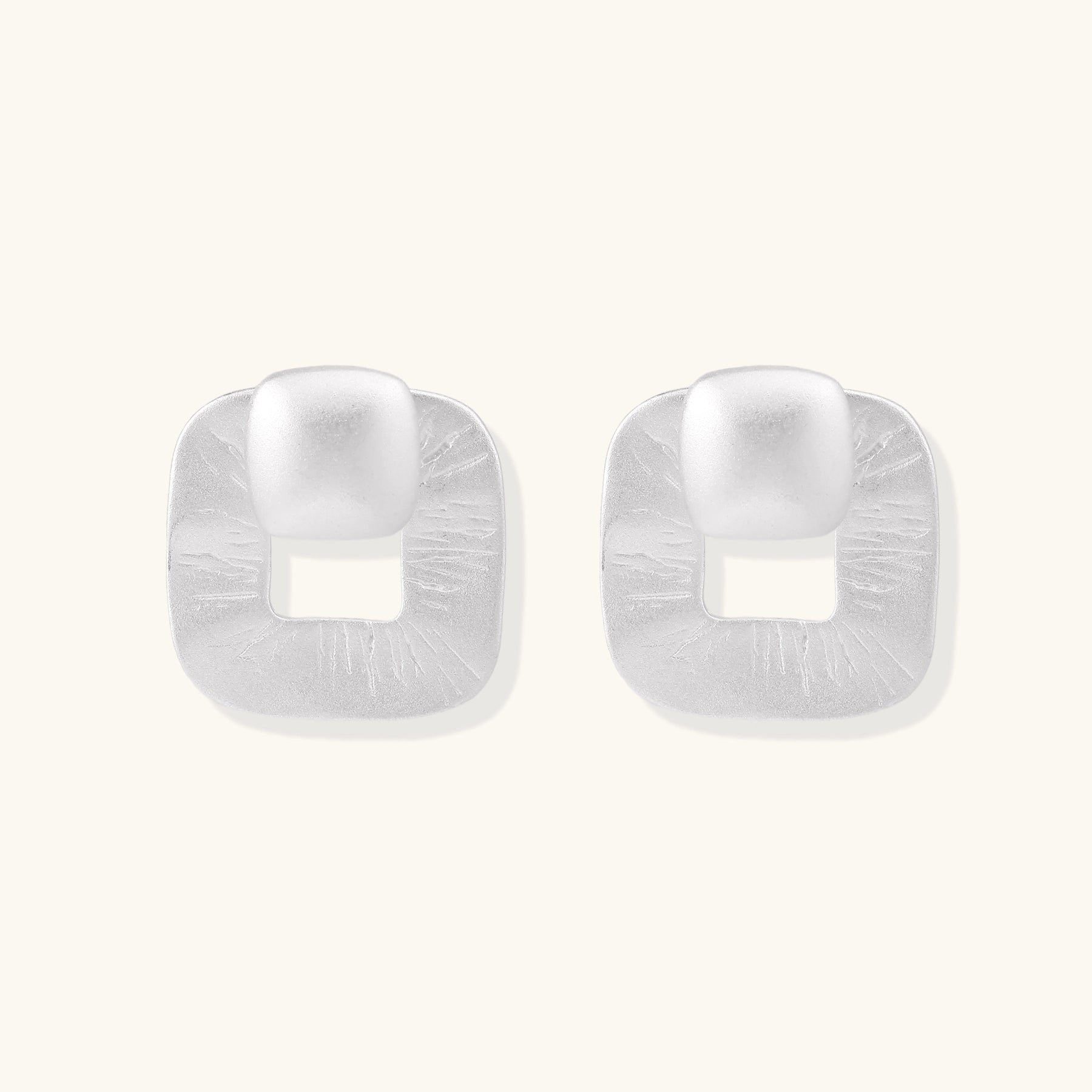 Geometric sterling silver square stud earrings with brushed texture and central square cutouts on white background.