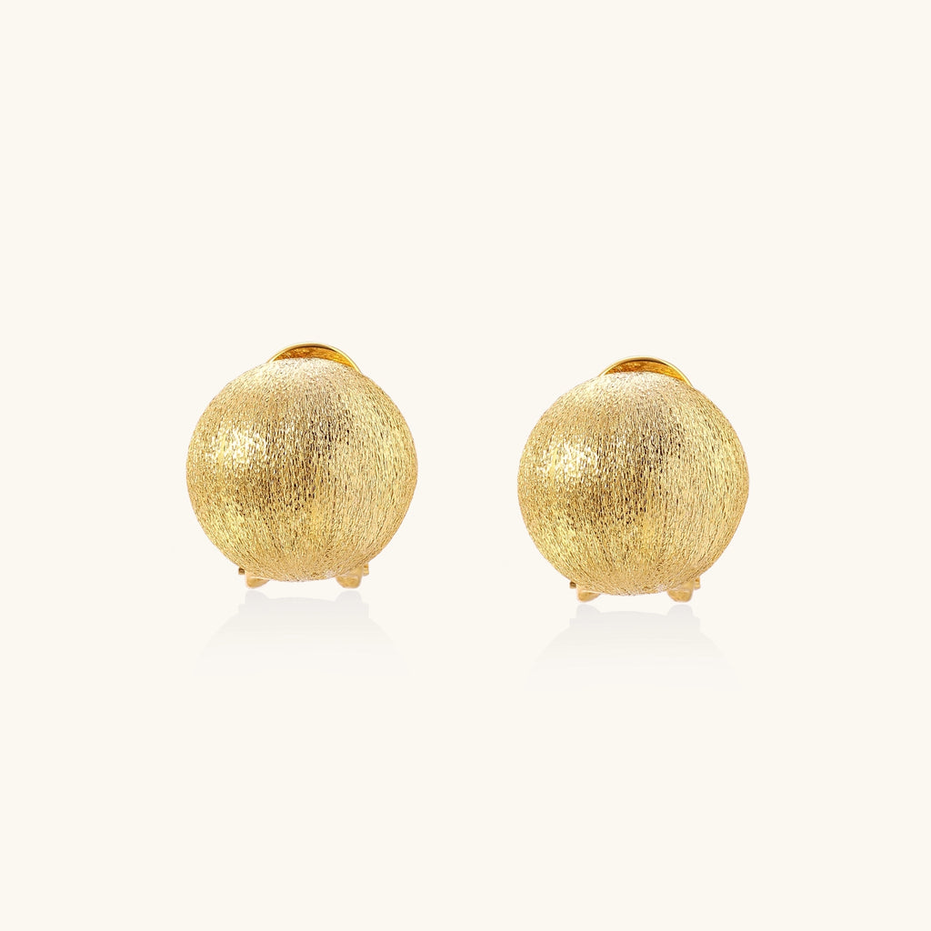 Close-up of textured gold-plated sterling silver dome clip-on earrings with brushed finish on white background.