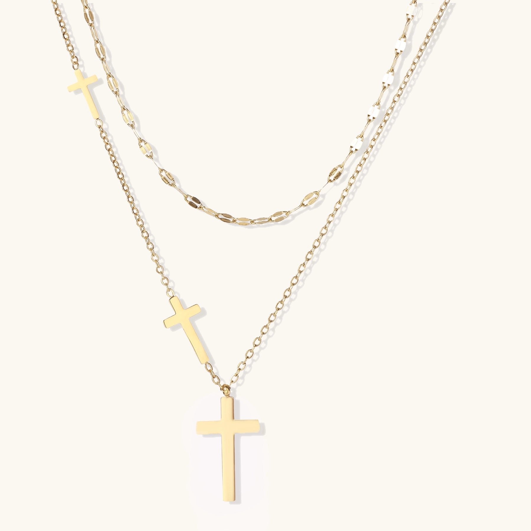 Two layered 14K gold-plated cross necklaces with adjustable chains on light background.