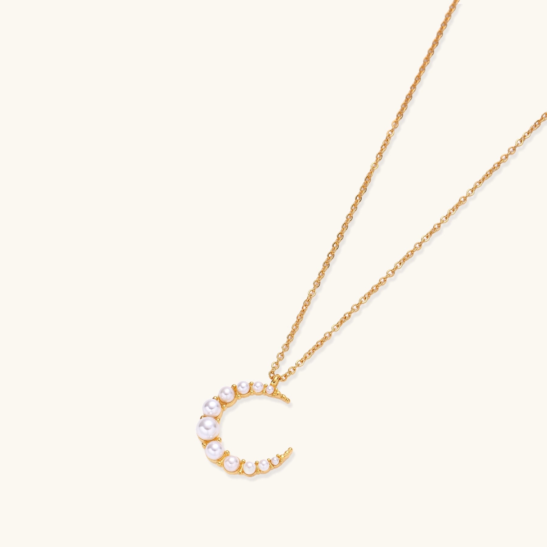 Delicate 18K gold plated necklace featuring crescent moon pendant with white shell pearl beads on neutral background.
