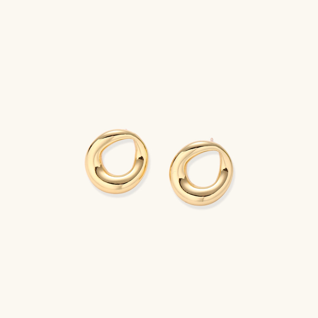 Pair of polished 18K gold-plated stainless steel oval loop stud earrings on cream background