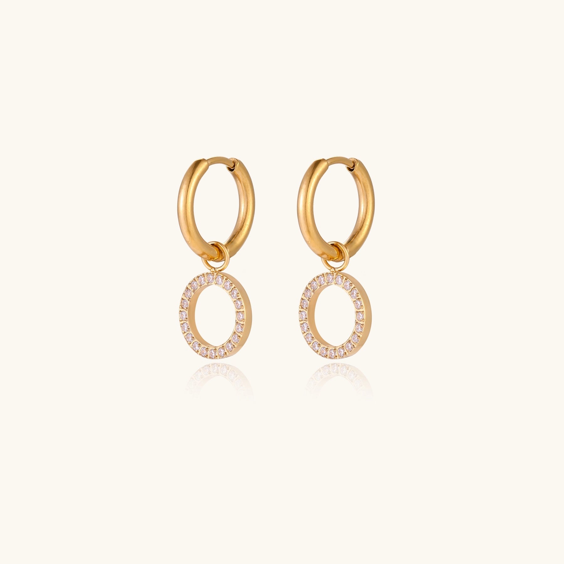 Gold-plated hoop earrings with circular cubic zirconia charm dangles displayed on neutral background.