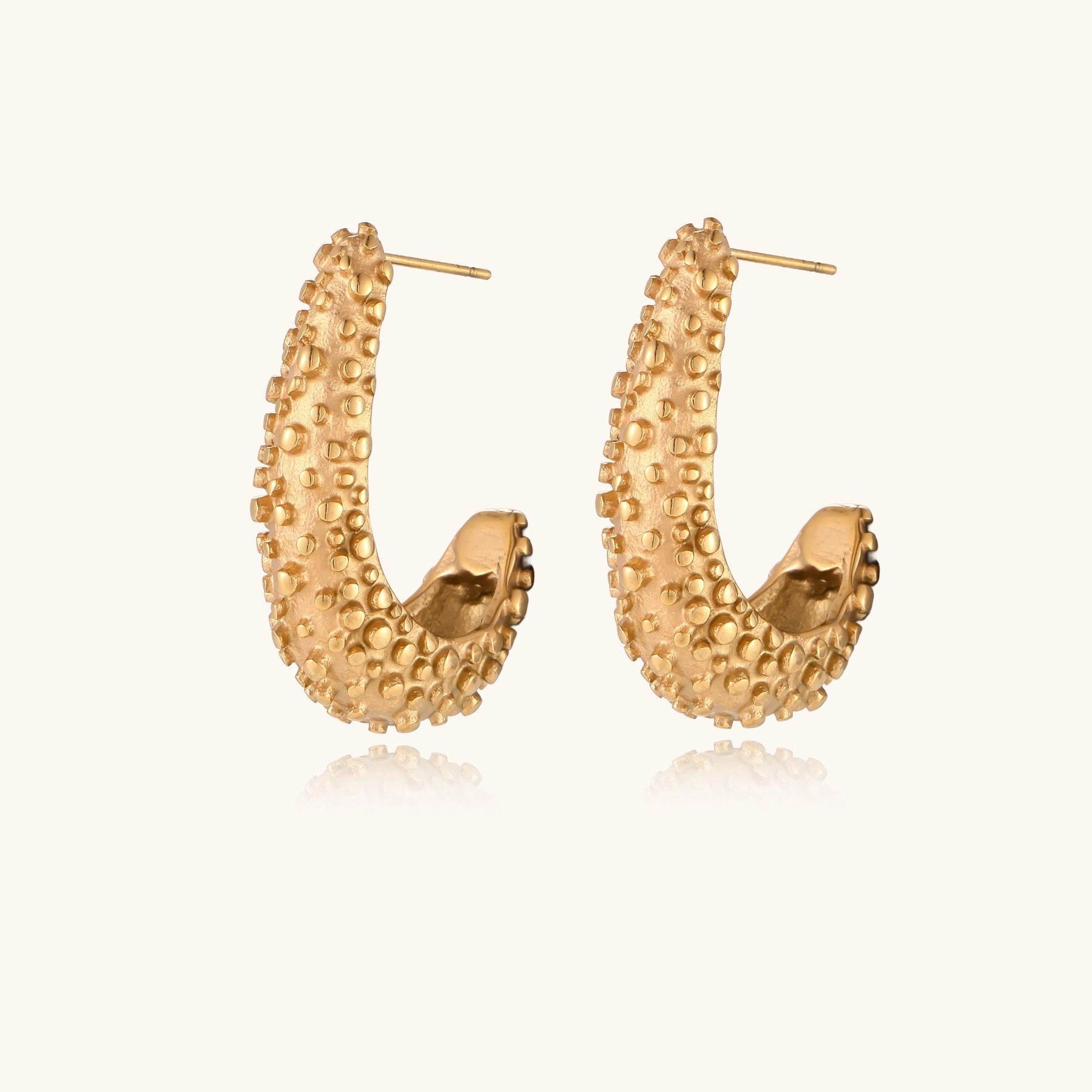Pair of gold-plated hoop earrings with raised dotted texture surface shown from multiple angles on white background.