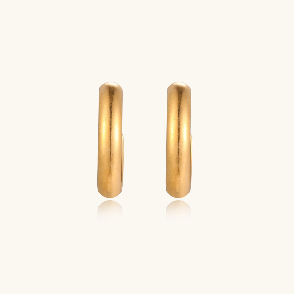 Four pairs of gold-plated stainless steel earrings including hoops and studs displayed on cream background
