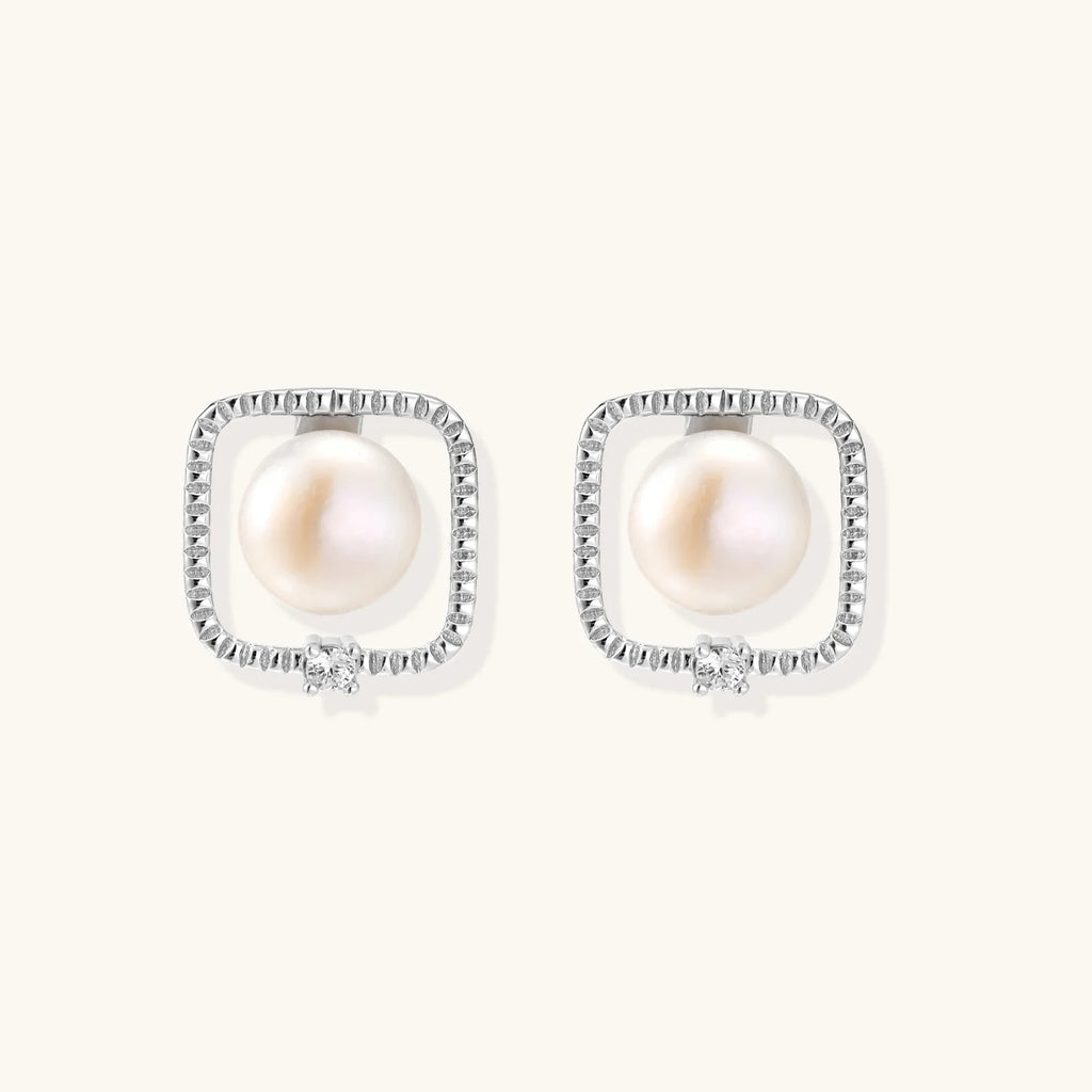 Rhodium-plated silver stud earrings with cushion frame, centered freshwater pearl, and tiny crystal accent