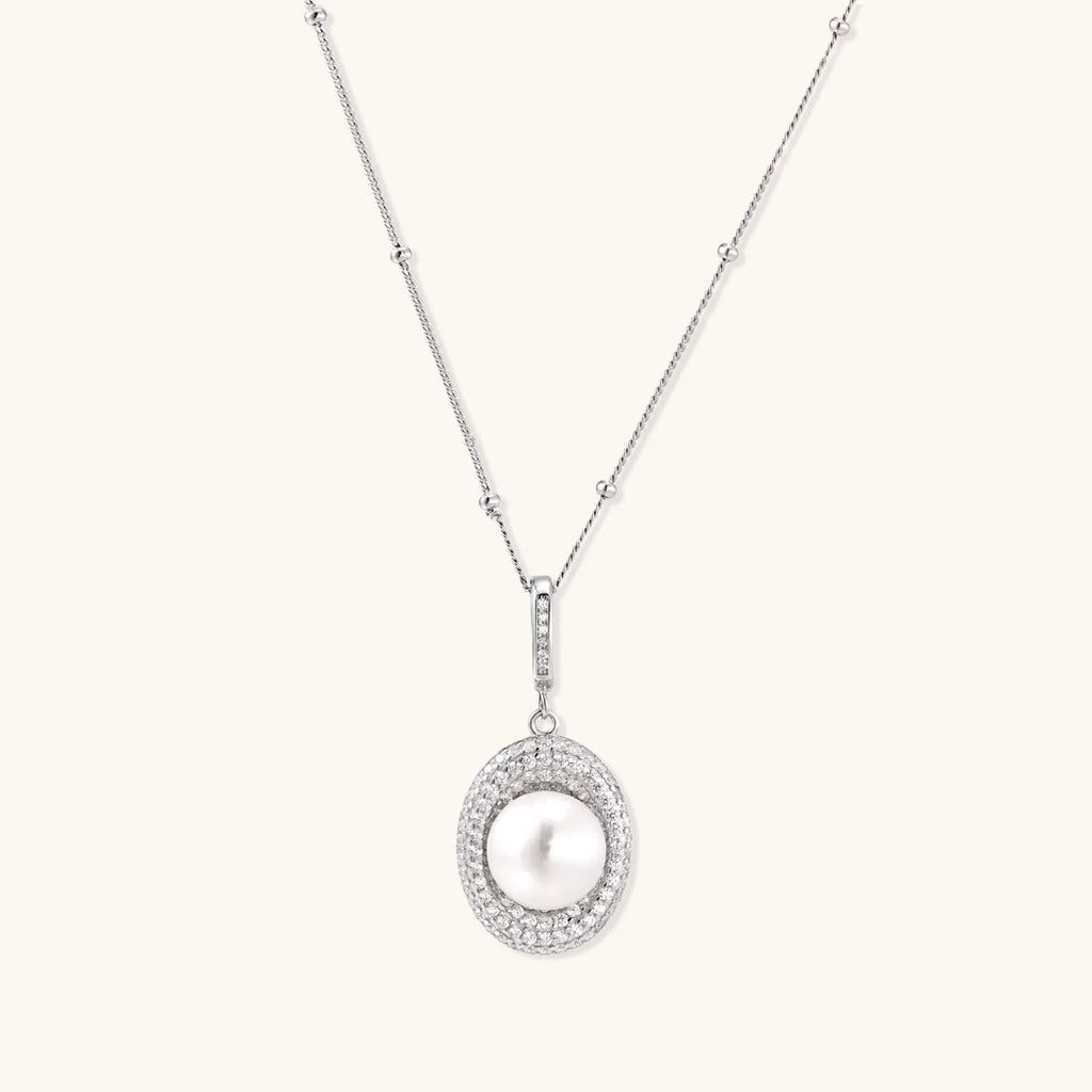 Oval sterling silver pendant with crystal halo surrounding a white freshwater pearl on delicate chain