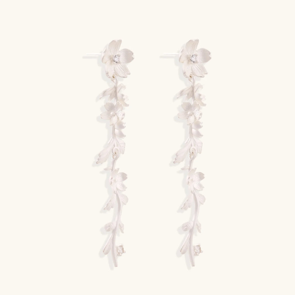Long sterling silver drop earrings with delicate floral vine design and crystal accents on white background