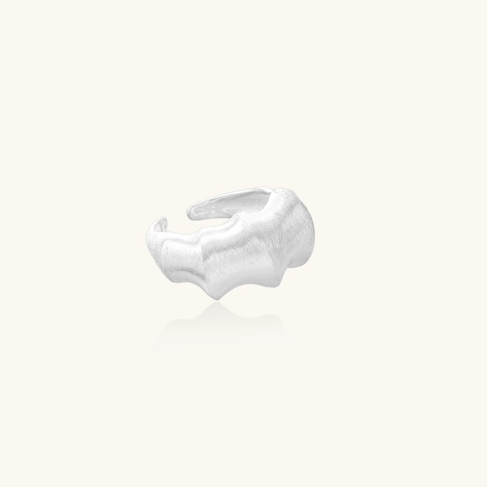 Brushed sterling silver ring with organic wave-like edges and adjustable cuff design on white background